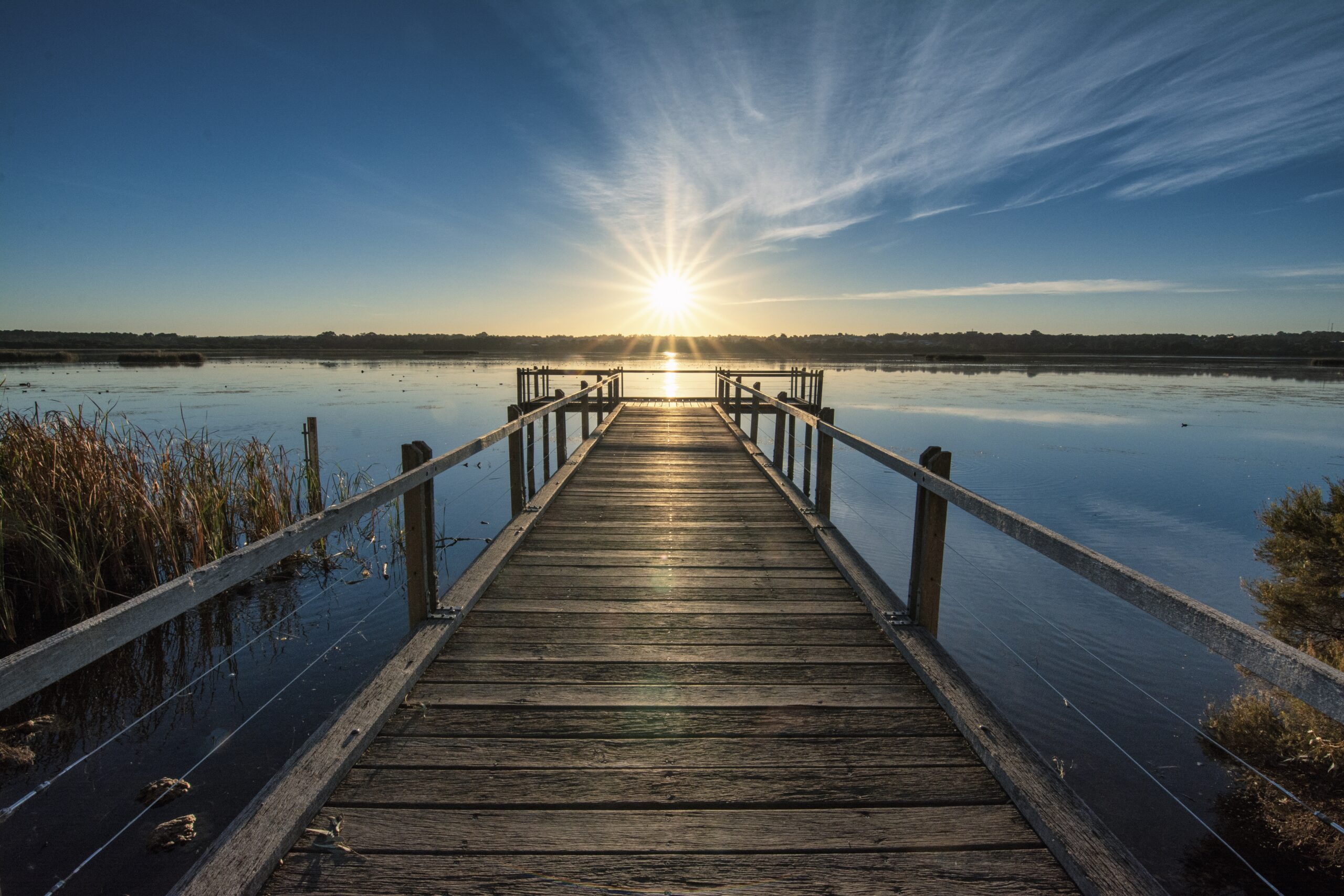 beautiful wooden pier by the calm ocean with the beautiful sunset over the horizon
